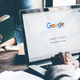 Man Using Laptop Browsing Google Website while another person reads a book